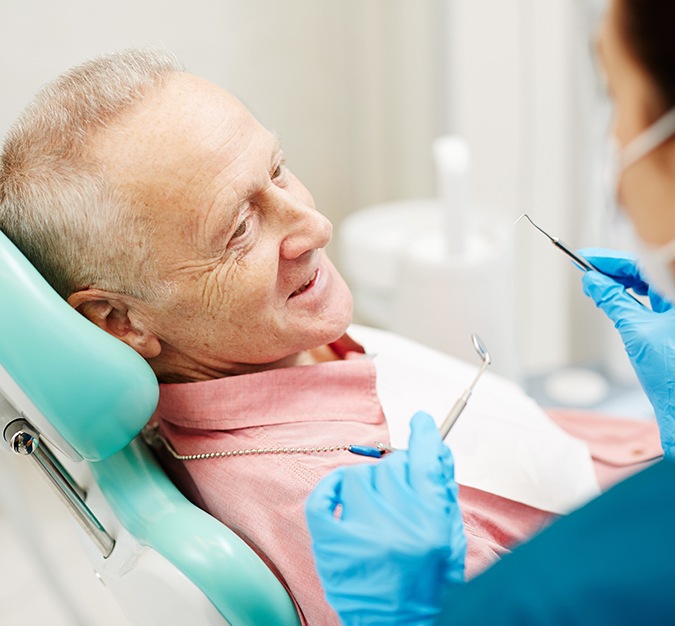 Older man smiling during a dental checkup and cleaning in San Antonio